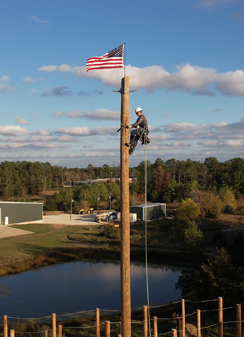 A man climbing a pole with an American flag at the top