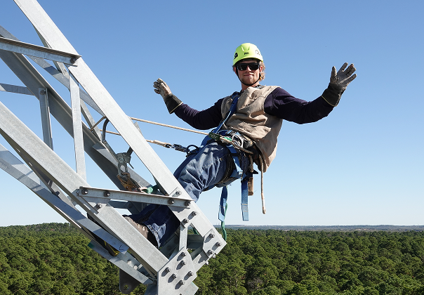 A man in a crane waving while suspended in the air