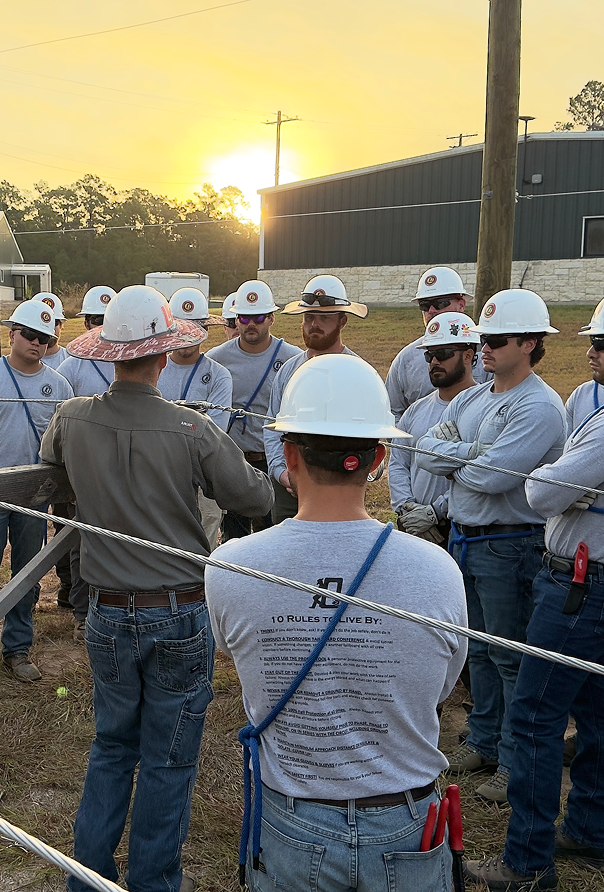 A team of working huddled around their foreman who is giving a safety demonstration
