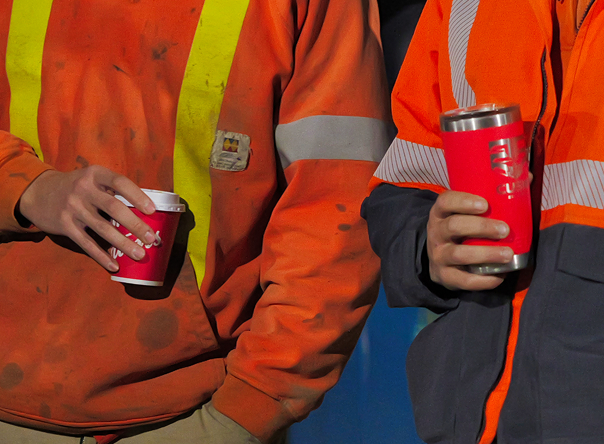 Men in safety clothing holding cups of coffee
