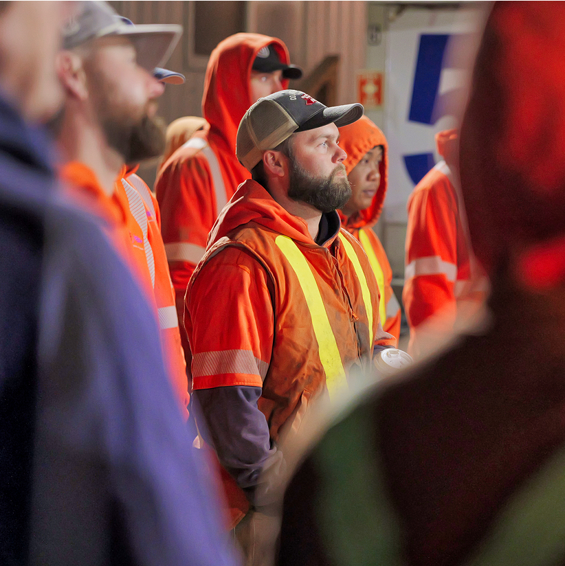 A man in safety equipment focused on the instructions of their foreman