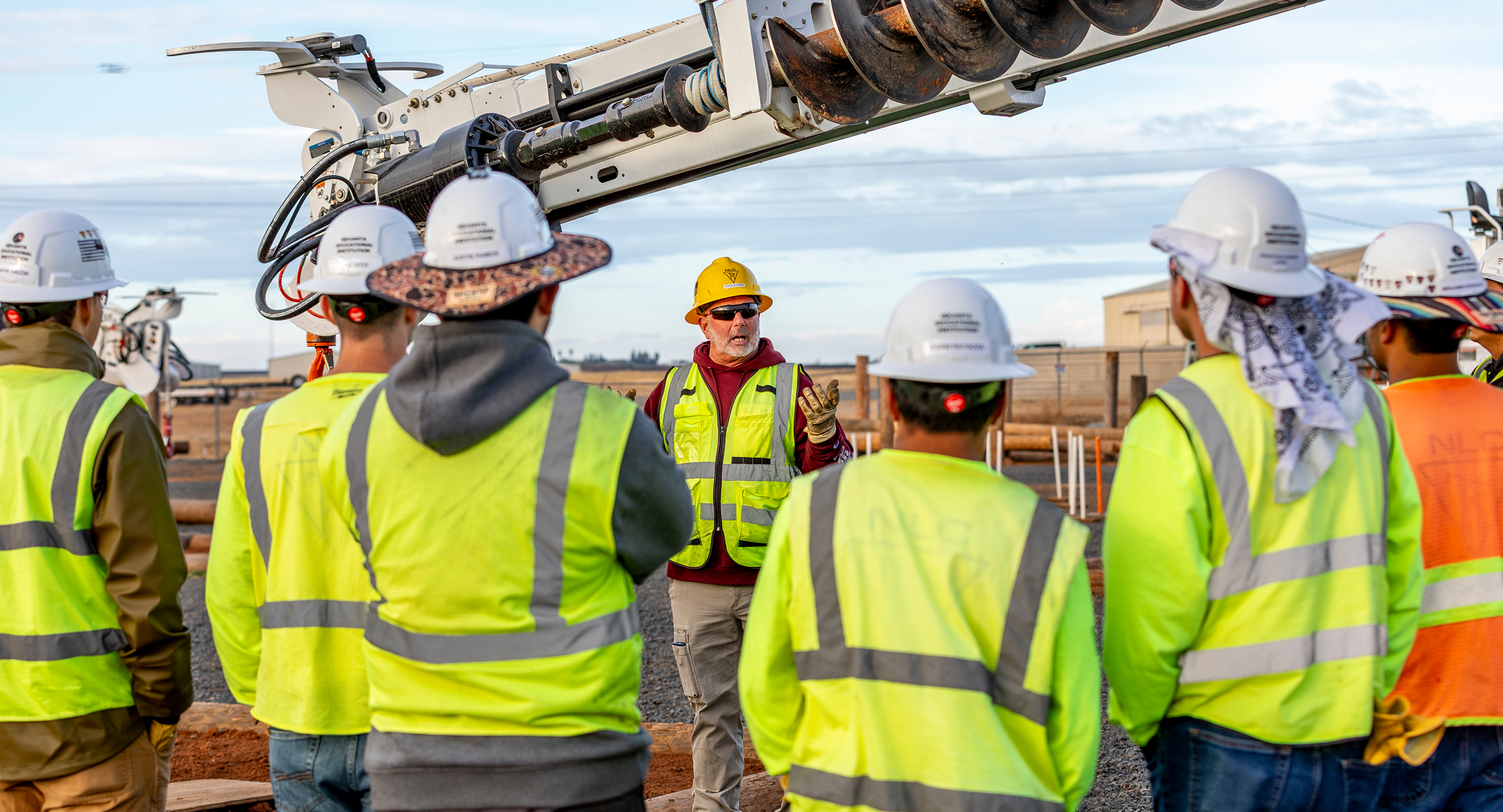 Image of a foreman talking to his crew in front of heavy machinery