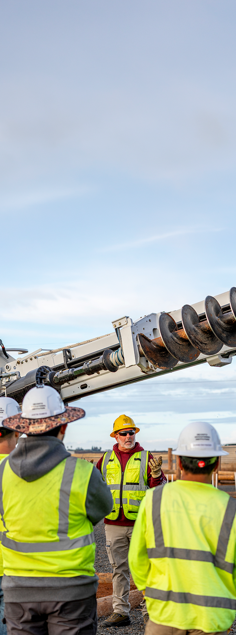 Image of a foreman talking to his crew in front of heavy machinery